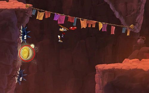 Przed drzwiami z okiem wskocz na półkę po lewej stronie i biegnąc po ścianie zdobądź M - Magiczne Małpki (300 L, 3:00); Droga Elektrunów (175 L) | Mistyczny Szczyt - Rayman Origins - poradnik do gry