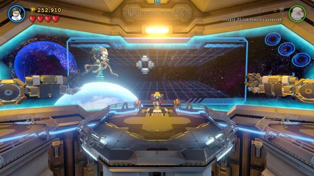 Jako Robin w kostiumie technicznym skorzystaj z konsoli w centralnej części i najedź przyciskami kierunku na statek Brainiaca by wysunąć tunel dokujący - Na Strażnicy Porządku | Opis przejścia Lego Batman 3 Poza Gotham - LEGO Batman 3: Poza Gotham - poradnik do gry