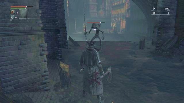 Po ich pokonaniu ruszaj w głąb ścieków, po dojściu do krawędzi widocznej na obrazku przyszykuj się na atak z lewej strony - czai się tam przeciwnik sprawnie wywijający długim kijem - Centrum Yharnam - Akwedukt | Opis przejścia Bloodborne - Bloodborne - poradnik do gry
