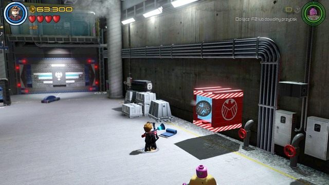 Podczas pobytu w garażu, przejdź na prawą stronę i zniszcz widoczną na obrazku, szklaną osłonę za pomocą Hawkeyea - Postacie | Loki, pierwsze kroki - sekrety | LEGO Marvels Avengers - LEGO Marvels Avengers - poradnik do gry