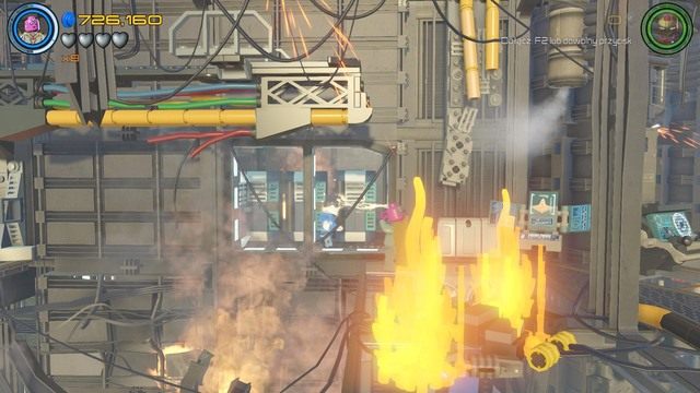 Jak dotrzesz do pożaru, który blokuje windę, zmień postać na Scarlet lub Visiona i podejdź do uwięzionego pracownika widocznego za szybą - Minizestawy | Chaos na Hellicarrierze - sekrety | LEGO Marvels Avengers - LEGO Marvels Avengers - poradnik do gry