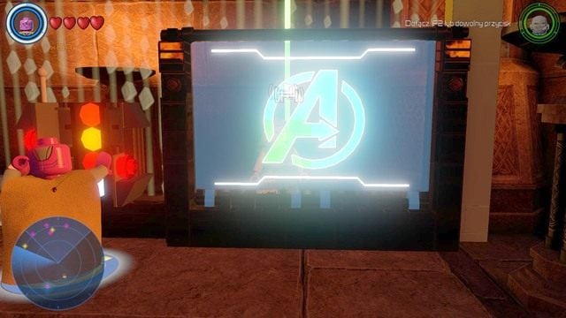 Po doprowadzeniu prądu do konsoli, skorzystaj z niej jako Vision i ułóż z części pokazanych na monitorze logo Avengers, które zostało pokazane na powyższym obrazku - Postacie | Asgard - sekrety | LEGO Marvels Avengers - LEGO Marvels Avengers - poradnik do gry