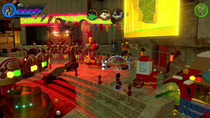 Przejdź na prawą stronę, czyli tam gdzie znajduje się karuzela, a znajdziesz małą budkę z widoczną szklaną osłoną na niej - Misja 6 - Potworna parada | Misje Gwenpool | Solucja LEGO Marvel Super Heroes 2 - LEGO Marvel Super Heroes 2 - poradnik do gry