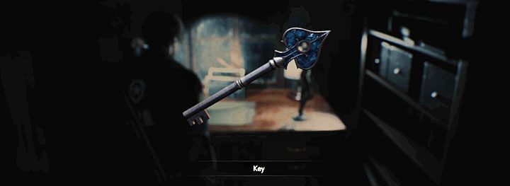 Klucz leży na biurku obok radia oraz figurki - Gdzie znaleźć niebieski klucz (pik) na komisariacie policji (Leon)? - Resident Evil 2 - poradnik do gry