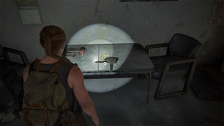 Kabura leży na małym prostokątnym stole w jednym z pomieszczeń - The Last of Us 2: Jak odblokować nowe kabury dla Ellie i Abby? - The Last of Us 2 - poradnik do gry