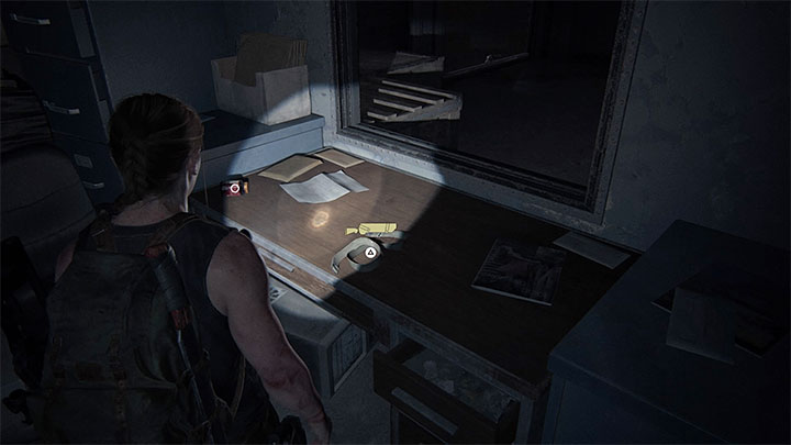 Kabura leży na dużym biurku w jednym z pomieszczeń - The Last of Us 2: Jak odblokować nowe kabury dla Ellie i Abby? - The Last of Us 2 - poradnik do gry