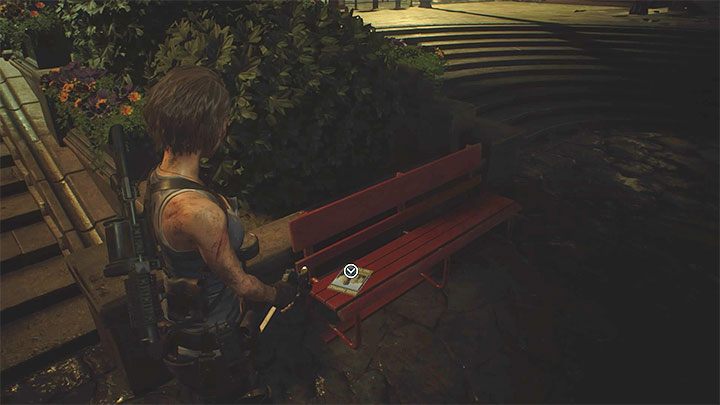 Broszura leży na czerwonej ławce niedaleko rzeki oraz miejsca rozpoczęcia eksploracji lokacji Clock Tower Plaza - Resident Evil 3: Plac przy wieży zegarowej sekrety, znajdźki - Resident Evil 3 - poradnik do gry