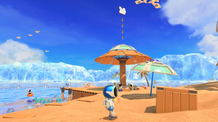 Przy brzegu znajduje się wielka parasolka, nad którą unoszą się monety i 3 element układanki - Astros Playroom: Plaża botów - solucja, opis przejścia - Astros Playroom - poradnik do gry