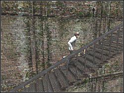 Po przejściu przez drzwi staniesz się świadkiem krótkiego filmiku, po którym będziesz musiał udać się biegiem w prawo, po kolejnych seriach schodów - Świat budynków (4) | Etap 5 w Silent Hill 4 The Room - Silent Hill 4: The Room - poradnik do gry